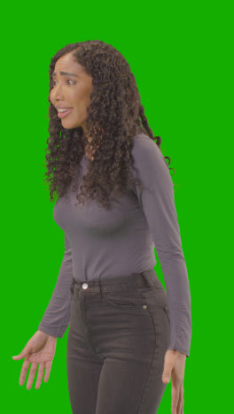 Vertical-Video-Three-Quarter-Length-Shot-Of-Angry-Looking-Vertical-Video-Woman-Shouting-At-Camera-Against-Green-Screen